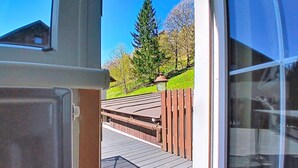 Une terrasse en bois qui mène à une maison offrant une vue dégagée sur un paysage verdoyant et des arbres.