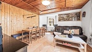 Un salon chaleureux avec des murs en bois, une table à manger avec des chaises, un canapé et une table basse.