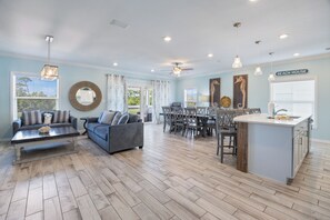 A spacious living area with a dining table, sofas, and a kitchen island. - Introducing Shells N Sea Beach Villa at Lost Key Golf & Beach Club! 4BR 4BA (Pensacola)