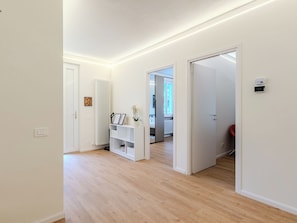 Ein Flur mit einer weißen Tür, einem weißen Konsolentisch mit Blumentopf und einem Heizkörper.