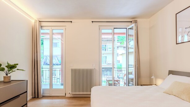 A bedroom with a bed, a dresser, a radiator, and a view through a sliding door. - Terrazza Segreta around Como Lake by Interhome (Carlazzo)