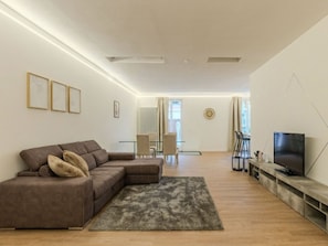 A modern living room with a sectional sofa, a flat-screen TV, and a dining area with a glass table and chairs. - Terrazza Segreta around Como Lake by Interhome (Carlazzo)
