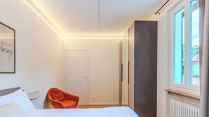 A bedroom with a bed, a chair, a wardrobe, a radiator, and a window with a view. - Terrazza Segreta around Como Lake by Interhome (Carlazzo)