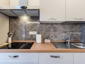A modern kitchen with a black countertop, stainless steel appliances, and a marble backsplash. - Terrazza Segreta around Como Lake by Interhome (Carlazzo)