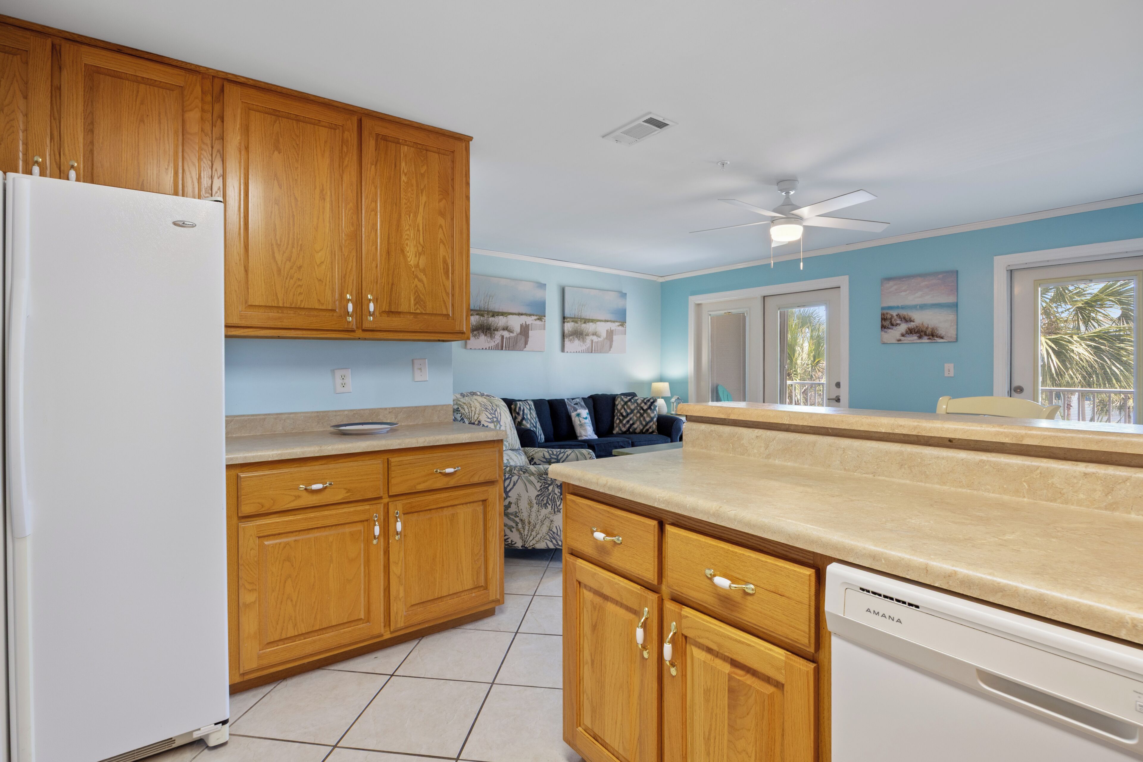 Una cocina con armarios de madera, un refrigerador blanco, lavavajillas y una zona de comedor con ventana.