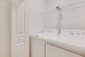 A laundry area with two white washing machines and a metal drying rack. - Golf + Poolside Fun! Extended Base in Ibis Landing (Lehigh Acres)