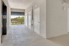 A corridor with a balcony, white doors, and a view of greenery. - Golf + Poolside Fun! Extended Base in Ibis Landing (Lehigh Acres)