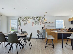 Eine moderne Küche mit Kochinsel, Barhocker und einem Essbereich mit Stühlen.