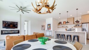 A modern kitchen with a central island, a dining area with a round table, and a ceiling fan. - Hot Tub & Views! Contemporary Yucca Valley Retreat (Yucca Valley)
