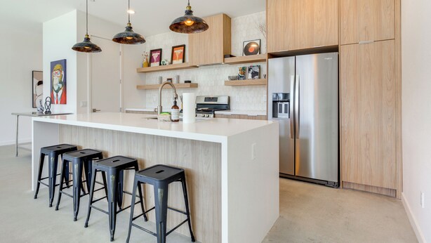 A modern kitchen with a central island, bar stools, pendant lighting, and stainless steel appliances. - Hot Tub & Views! Contemporary Yucca Valley Retreat (Yucca Valley)