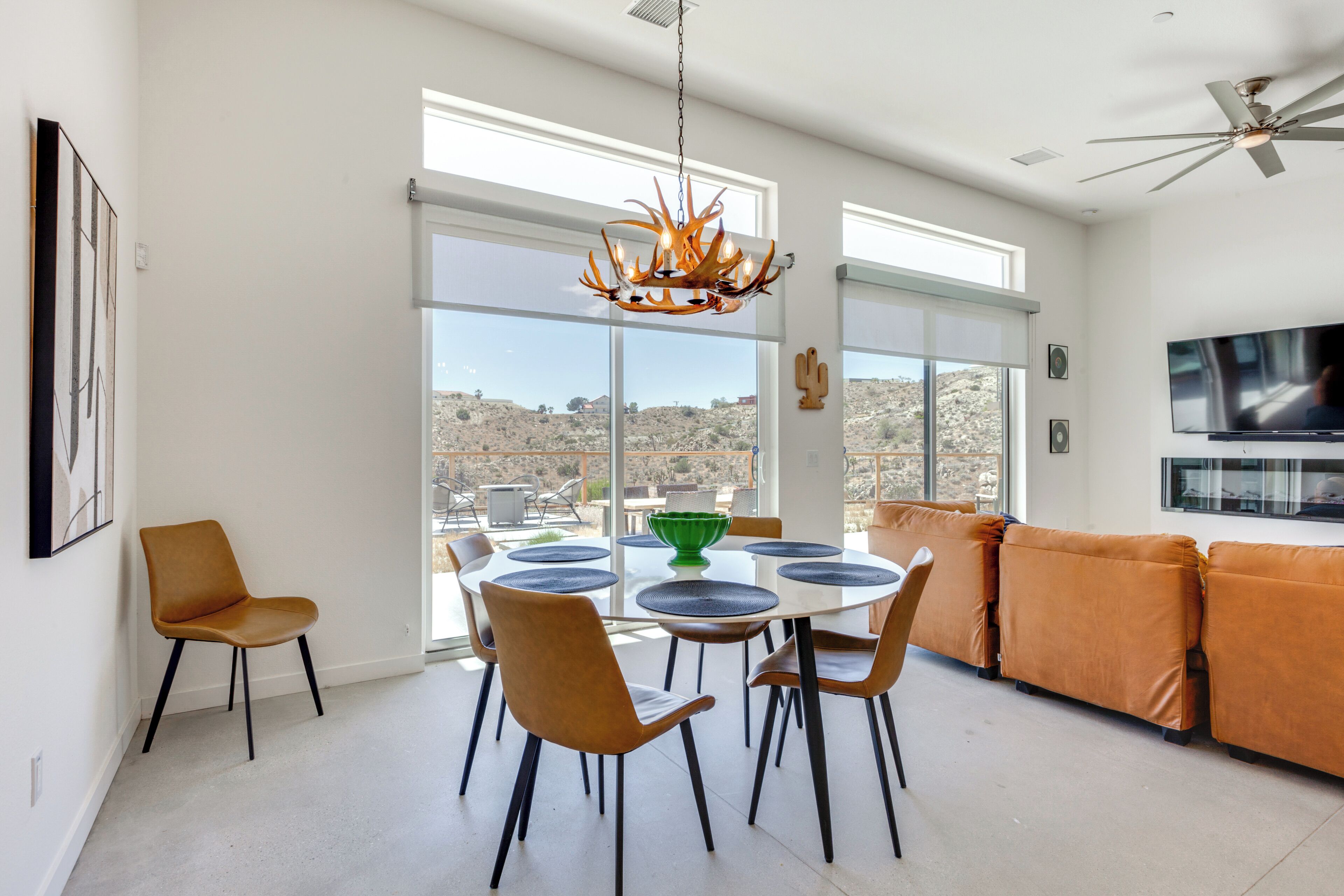 A modern dining area with a round table, chairs, and a chandelier.