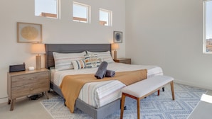 A bedroom with a bed, bedside tables, a bench, and two windows. - Hot Tub & Views! Contemporary Yucca Valley Retreat (Yucca Valley)