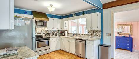 A kitchen with white cabinets, a stainless steel dishwasher, and a wooden floor.