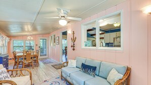 Un intérieur chaleureux avec un coin repas, un canapé et un ventilateur de plafond.