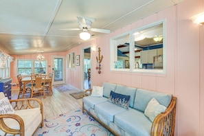 A cozy interior with a dining area, a sofa, wicker furniture, and a ceiling fan.