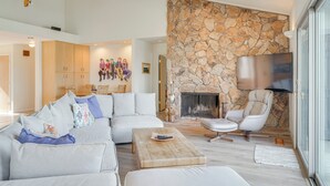 Ein modernes Wohnzimmer mit Kamin aus Stein, einem großen Sofa, einem Couchtisch und einem Fernseher.