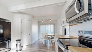 Een moderne keuken met roestvrijstalen apparatuur, een houten aanrecht en een eethoek met een tafel en stoelen.
