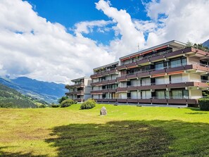 Ein mehrstöckiges Hotel mit Balkonen vor einer Bergkulisse.