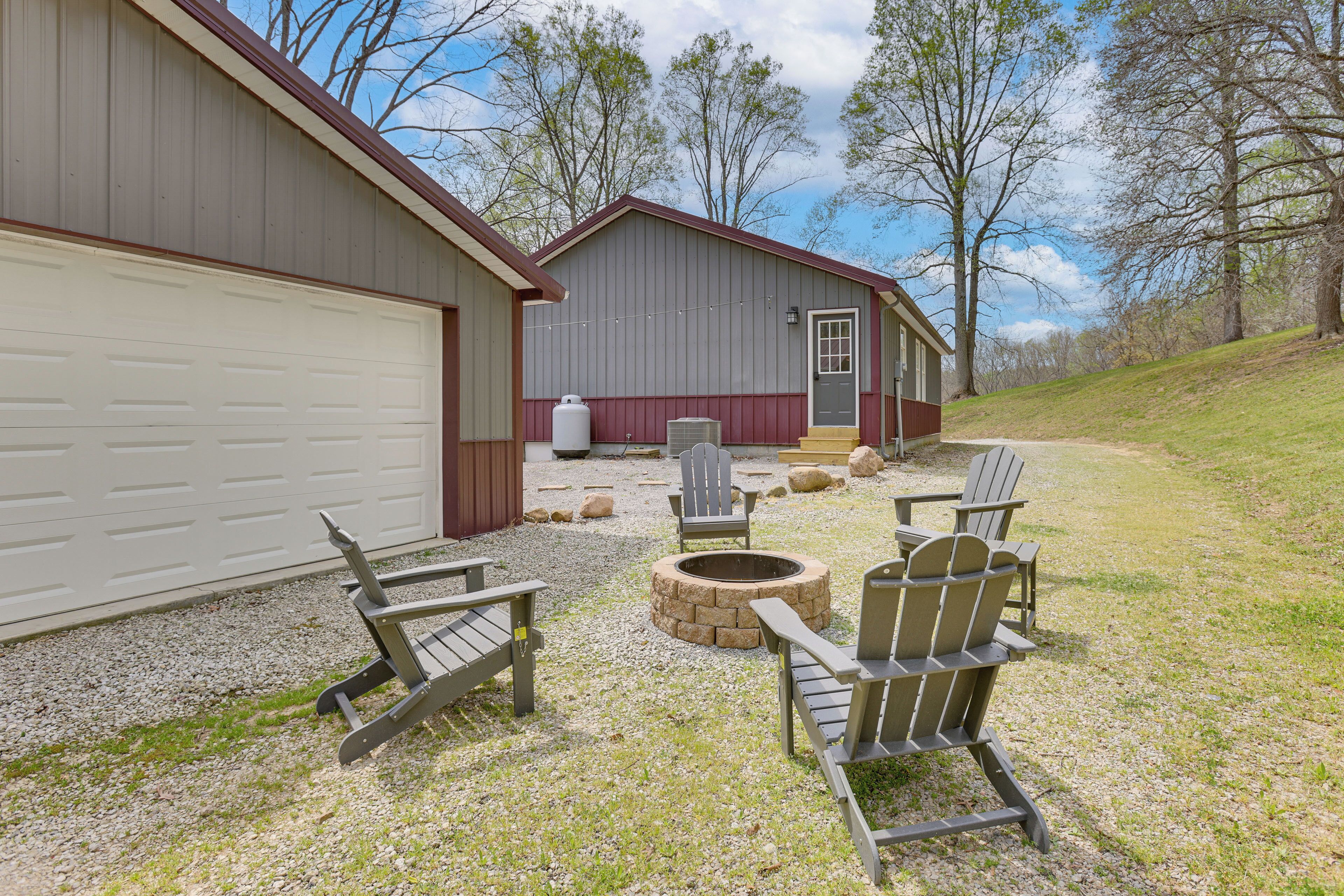 Een gebouw met een garage, vuurkorf en Adirondack stoelen.