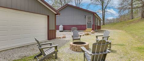 A building with a garage, a fire pit, and Adirondack chairs.