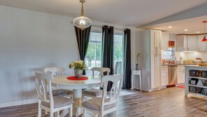 A dining area with a round table, white chairs, a chandelier, and a view of the kitchen. - Quiet North Florida Charm Awaits (Mcalpin)