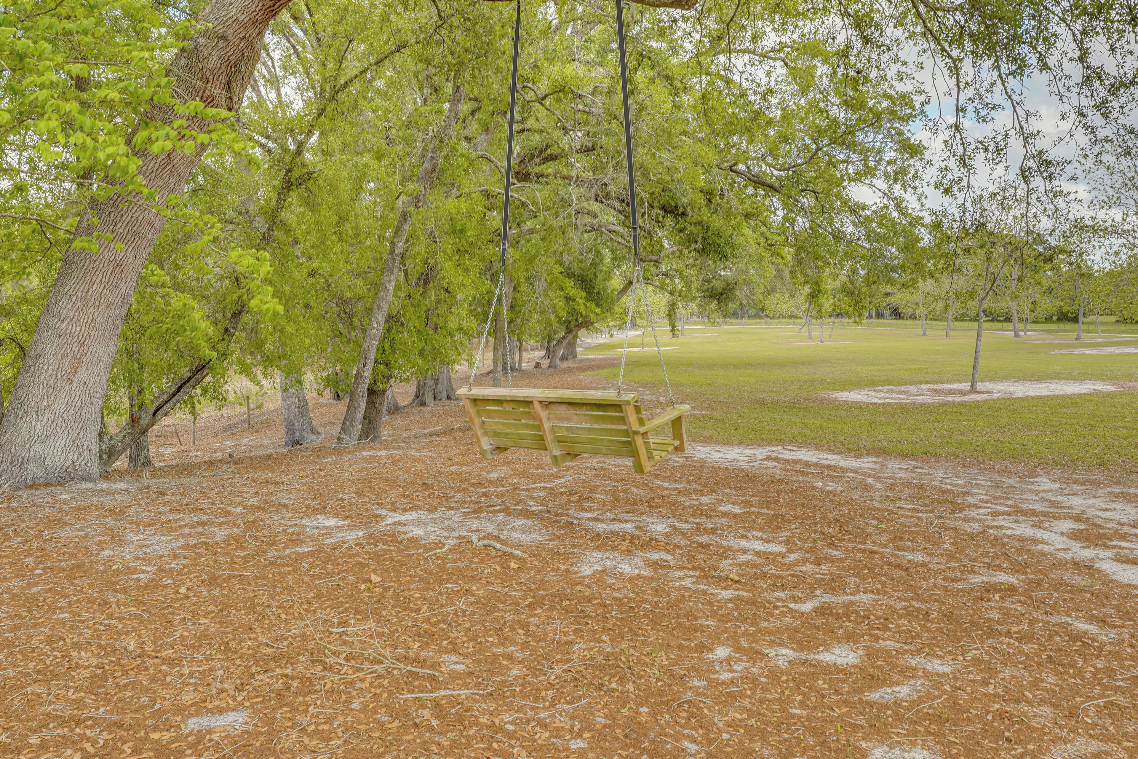 A park with a wooden swing set, trees, and a grassy area.