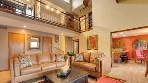 A spacious living area with a high ceiling, a balcony with a wrought iron railing, and a dining area with a red chair. - 2 Private Pools! Stunning Southaven Group Getaway (Southaven)