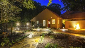 A well-lit wooden house with a stone pathway, a fenced garden, and a fire pit. - 2 Private Pools! Stunning Southaven Group Getaway (Southaven)