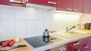 Una cocina moderna con armarios rojos, un lavamanos de acero inoxidable y una estufa empotrada.