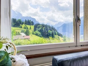 A room with a large window offering a view of a mountainous landscape. - Bristol Apt. M by Interhome (Wengen)