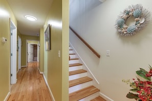 A hallway with wooden flooring and a staircase with a wooden handrail. - Walk to Garden City Pier & Beach! Group Getaway (Murrells Inlet)