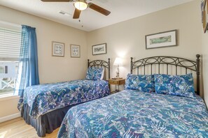 A bedroom with two beds, a ceiling fan, a window with curtains, and framed pictures on the wall. - Walk to Garden City Pier & Beach! Group Getaway (Murrells Inlet)