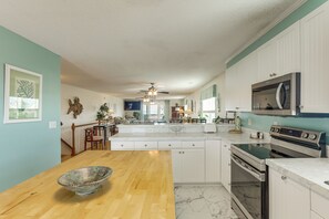 A modern kitchen with white cabinets, a wooden countertop, and a large island. - Walk to Garden City Pier & Beach! Group Getaway (Murrells Inlet)