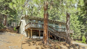 Eine Lodge mit Balkon, Treppe und bewaldeter Umgebung.