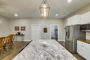 Una cocina con una isla grande, sillas de madera, un refrigerador y una lámpara colgante.