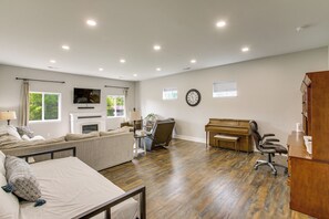 A spacious living room with a sofa, a piano, a television, and a fireplace.
