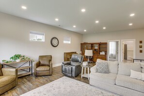 A spacious living room with a leather sofa, a leather armchair, a small table with a lamp, and a decorative rug.