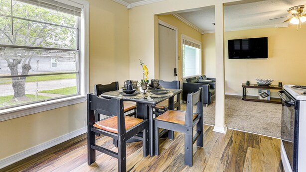A dining area with a table set for four, a television mounted on the wall, and a ceiling fan. - Port Arthur Homebase: Work, Dine & Play! (Port Arthur)