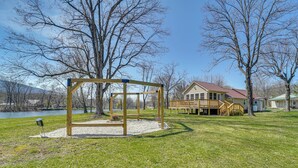 A park with a swing set, a wooden deck, and a house with a red roof. - 'slate Drake Cabin' on Penns Creek w/ Deck & BBQ (Millmont)