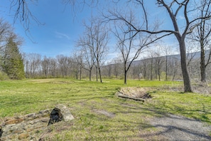 A grassy field with a stone wall and trees.