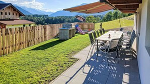 A patio with a table and chairs, a barbecue grill, and a children's play area.