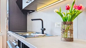 A modern kitchen with a stainless steel countertop, a black faucet, and a vase with tulips.