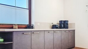 A kitchen with a window, cabinets, and a countertop with a coffee maker.