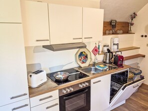 Eine kompakte Küchenzeile mit Herd, Toaster, Spüle und Geschirrspüler.