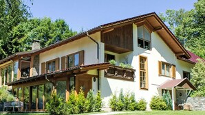 Une maison à deux étages dotée d’un balcon, de grandes fenêtres et d’une cheminée en pierre.
