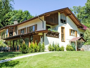 Ein zweistöckiges Haus mit einem Balkon, großen Fenstern und einem Steinkamin.