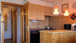 A kitchen with wooden cabinets, a built-in dishwasher, a microwave, and pendant lights. - Beautiful apartment for 5 people with TV and balcony (Veysonnaz)