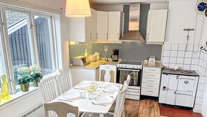 Une cuisine moderne avec des meubles blancs, une cuisinière et un coin repas aménagé pour quatre personnes.