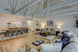 A spacious living area with a high ceiling, a dining table, sofas, and a coffee table. - Sunset Rentals | Queens Grant 684 | Dog Friendly (Hilton Head Island)