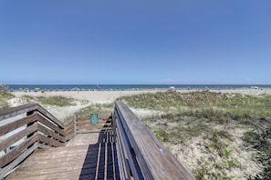 A wooden boardwalk leading to a beach with a clear view of the ocean and beach umbrellas. - Sunset Rentals | Queens Grant 684 | Dog Friendly (Hilton Head Island)